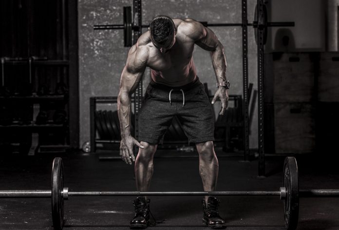 Un bodybuilder in procinto di sollevare un bilanciere pesante con le mani